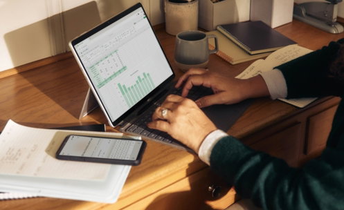Person working on laptop at a wooden desk.